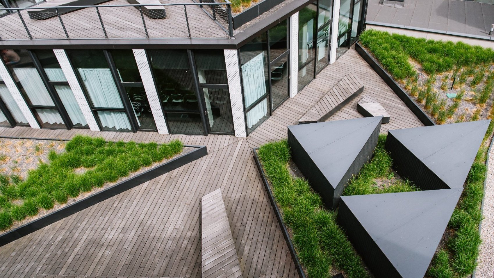 Na zdjeciu zielony dach budynku Za Bramką, widać trawę i ławki