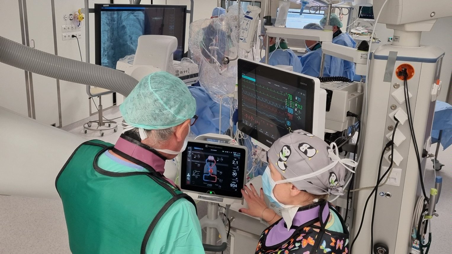 Zdjęcie przedstawia lekarzy na sali operacyjnej, stojących przy monitorze.