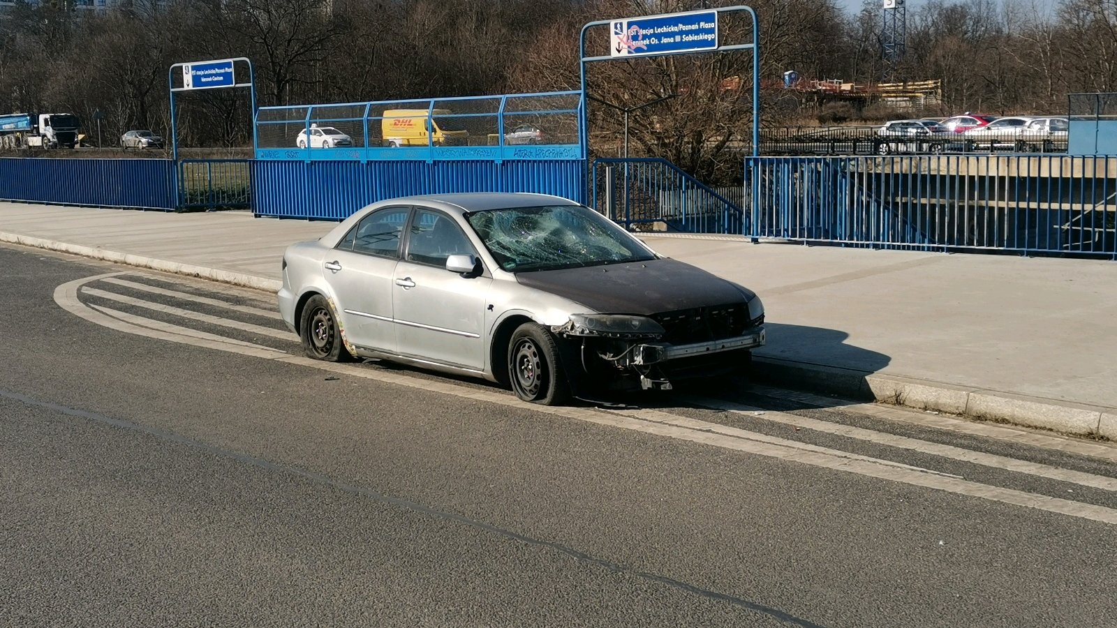 Zdjęcie przedstawia zniszczony samochód stojący na poboczu ulicy.