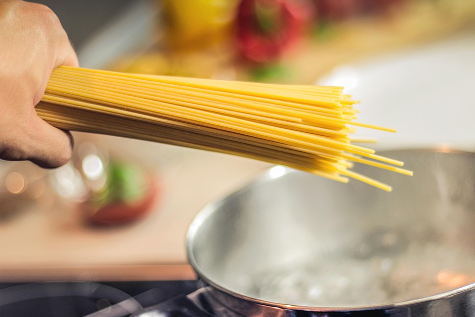 Można ugotować idealny makaron al dente, jednocześnie dbając o domowy budżet i planetę, fot. Pixabay Ręka trzymająca makaron spaghetti, który zaraz trafi do garnka z gotującą się wodą.