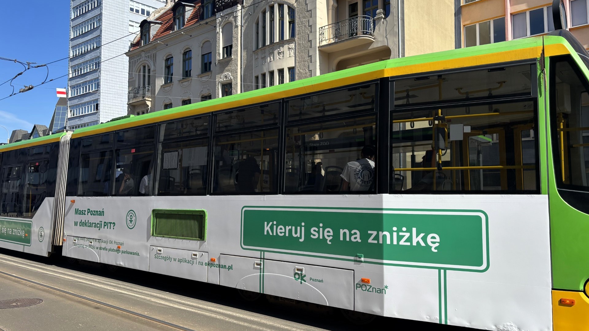 Pozostawienie cen Biletów Metropolitalnych bez zmian to nie tylko finansowa ulga dla pasażerów... Tramwaj oklejony naklejkami z OK Poznań, jadący pomiędzy kamieniczkami.