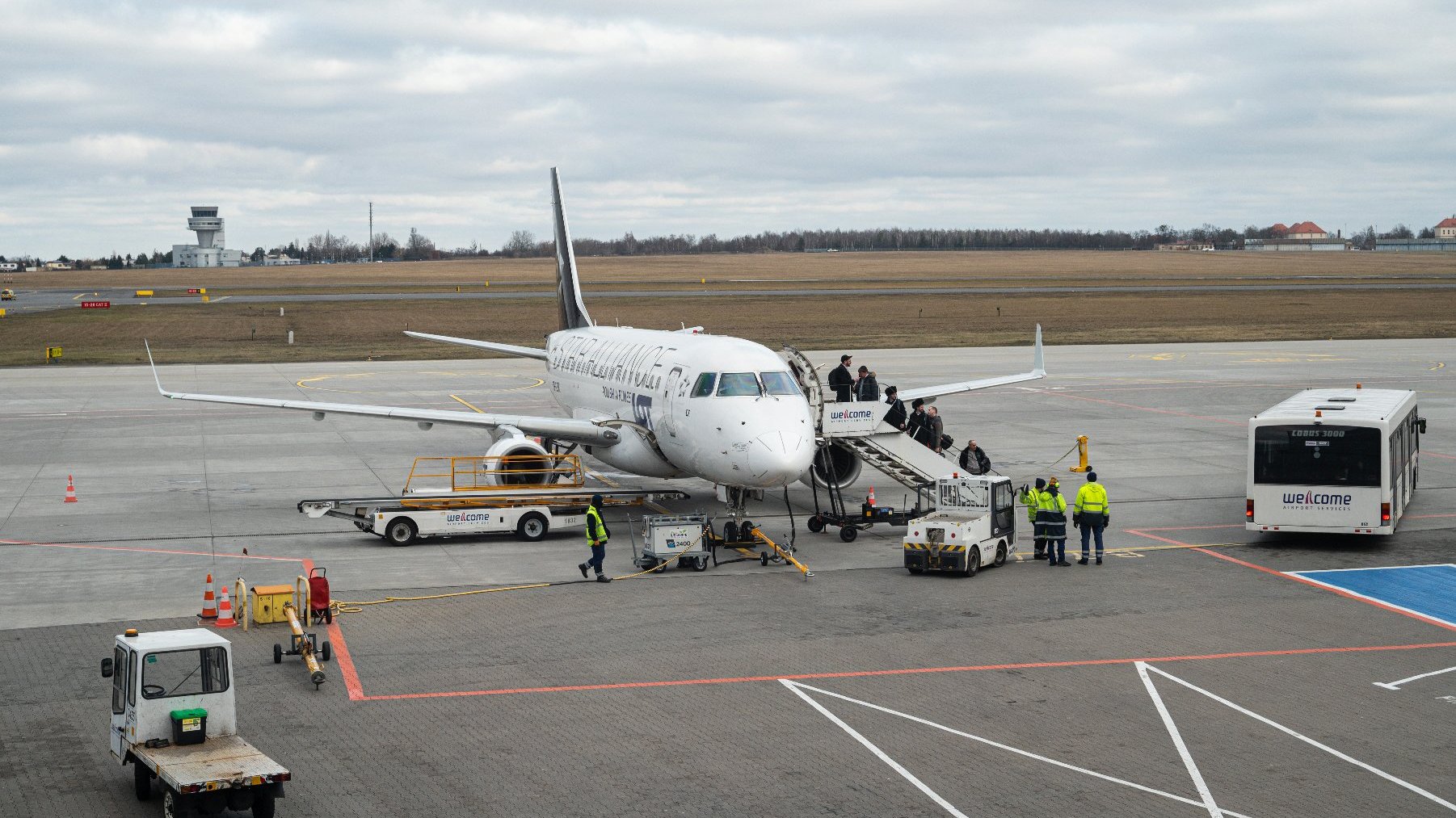 Samolot stojący na pasie, do którego wsiadają pasażerowie