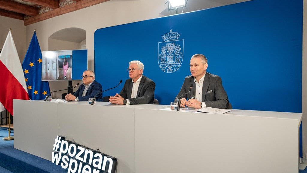 Na zdjęciu trzech mężczyzn za stołem konferencyjnym, w środku prezydent Poznania