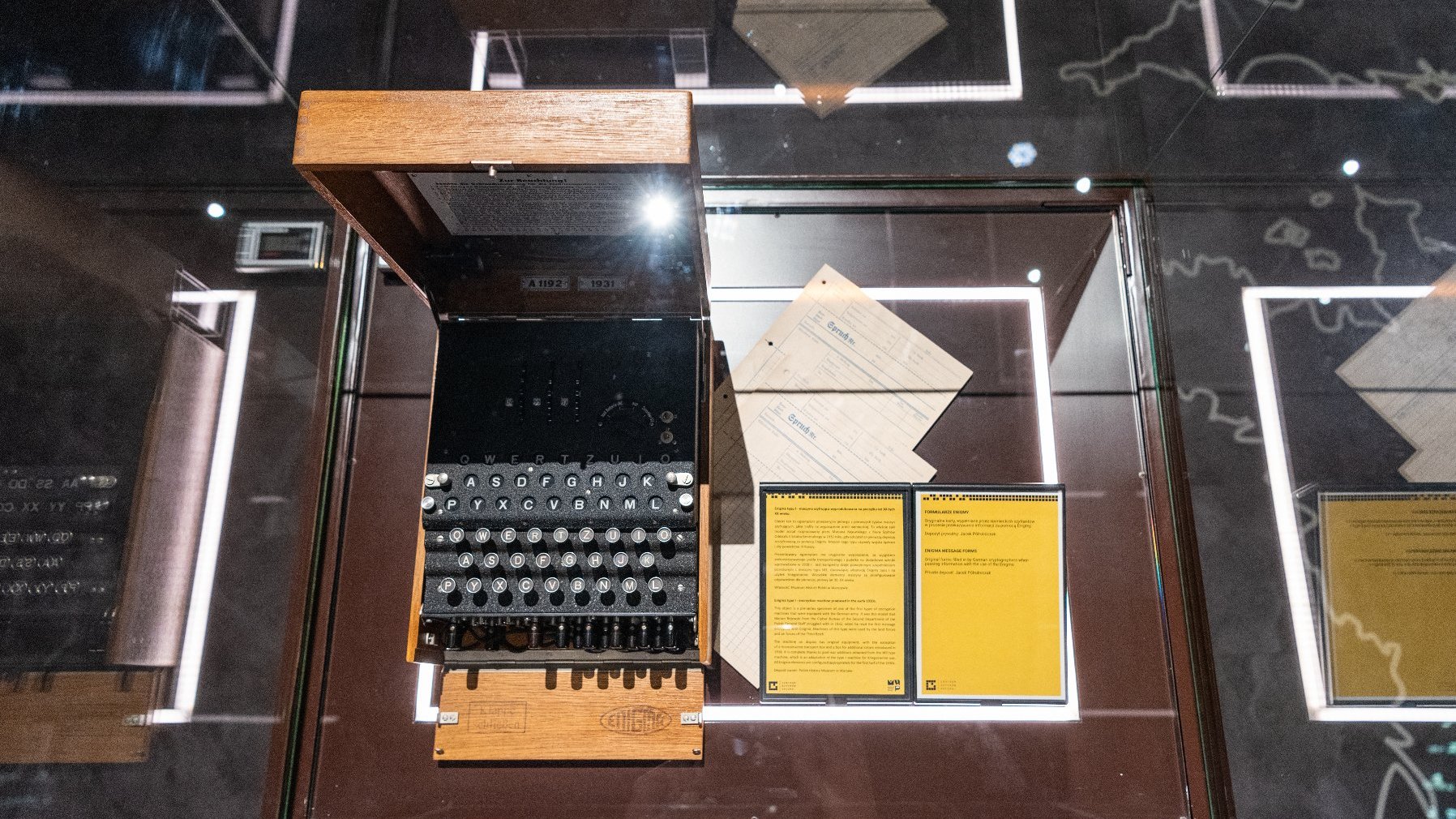 Zdjęcie przedstawia widok z góry na niemiecką maszynę szyfrującą Enigma umieszczoną w gablocie.