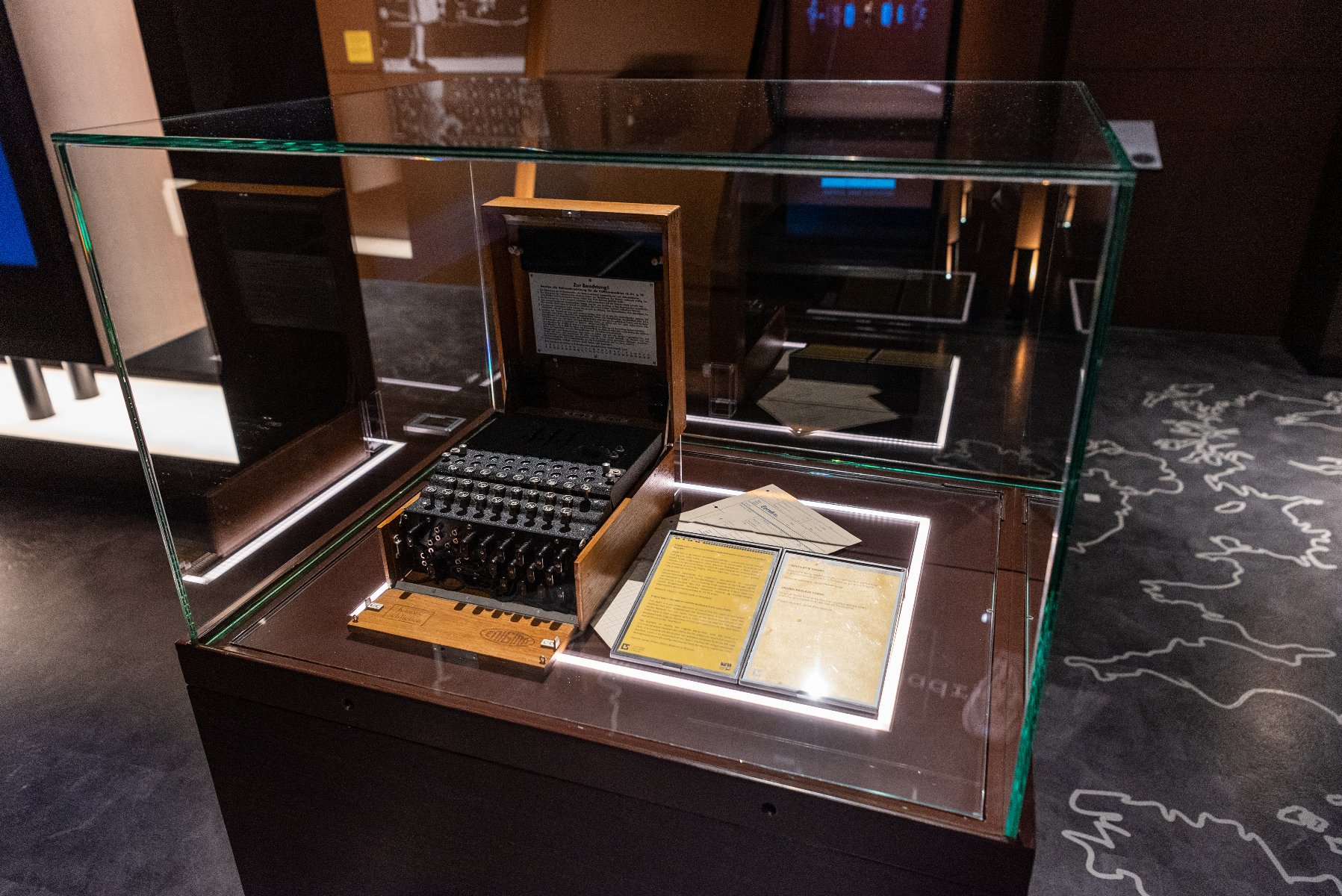 Zdjęcie przedstawia niemiecką maszynę szyfrującą Enigma umieszczoną w gablocie. - grafika artykułu