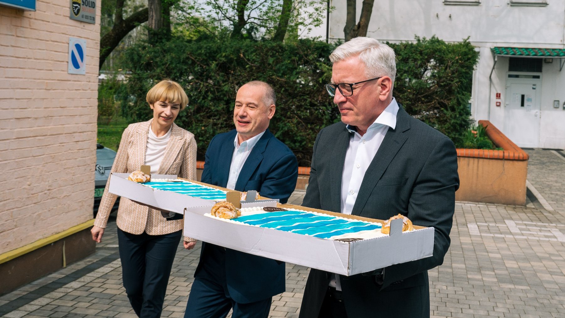 Na zdjęciu trzy osoby - w tym prezydent Poznania - niosące tort