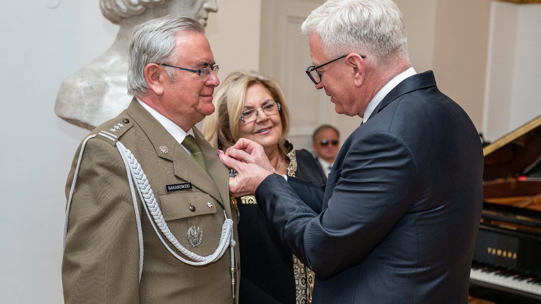 Na zdjęciu prezydent Poznania przypinający medal mężczyźnie, obok którego stoi jego żona