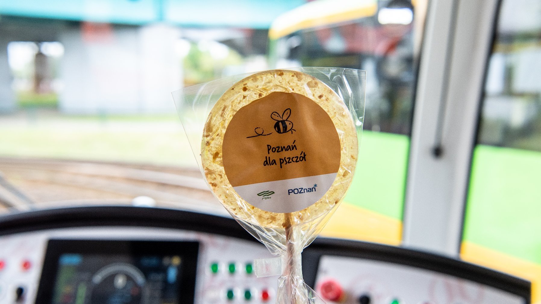 Na zdjęciu wnętrze tramwaju, na pierwszym planie lizak z napisem: poznań dla pszczół