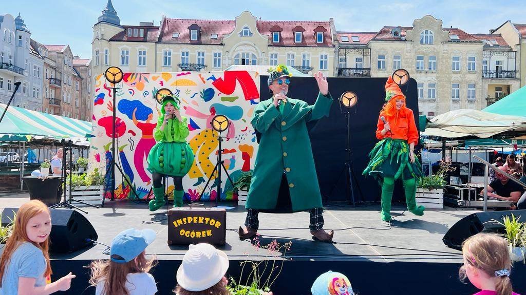 Na zdjęciu przebrani aktorzy na scenie na powietrzu, przed sceną stoją dzieci