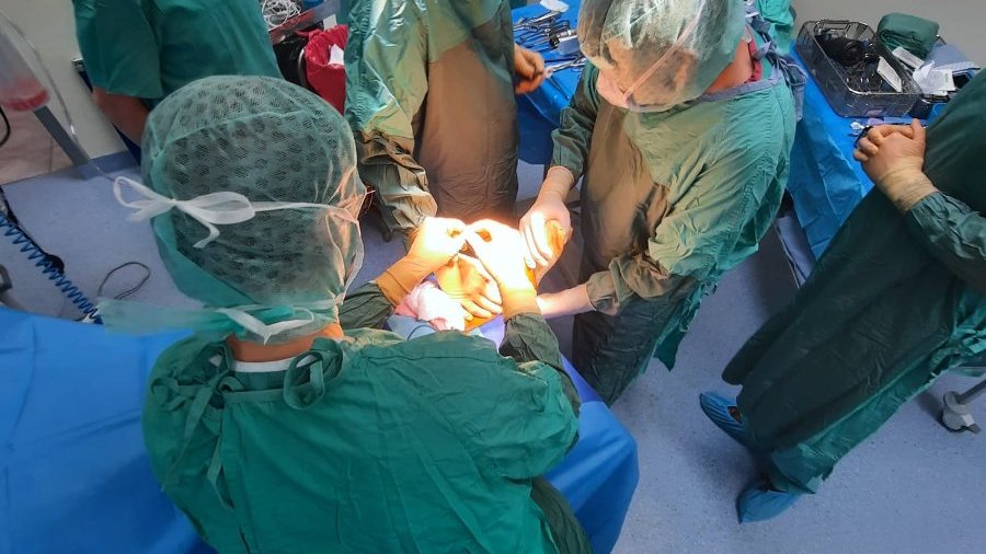Na zdjęciu zespół chirurgów podczas operacji, wokół stołu