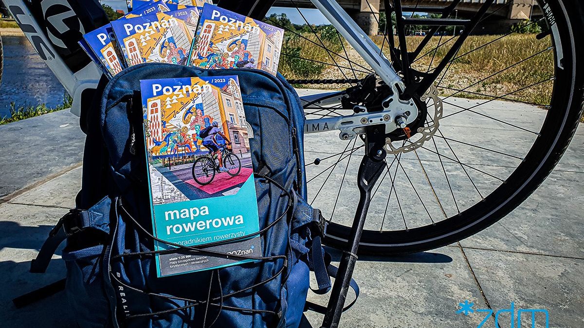 Na zdjęciu mapy rowerowe wystające z plecaka opartego o rower w okolicy mostu św. Rocha