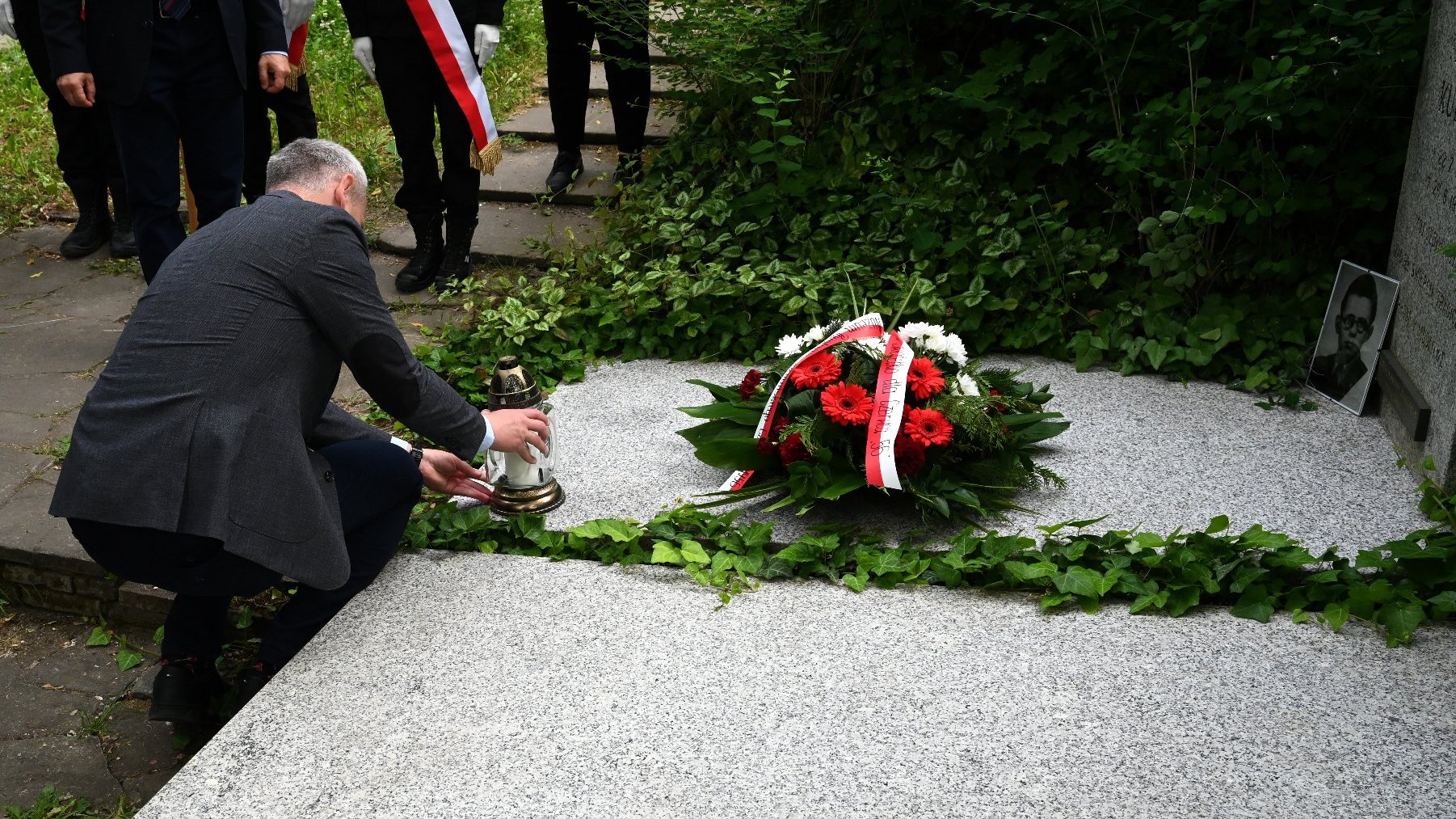 Na zdjęciu mężczyzna stawia znicz na grobie