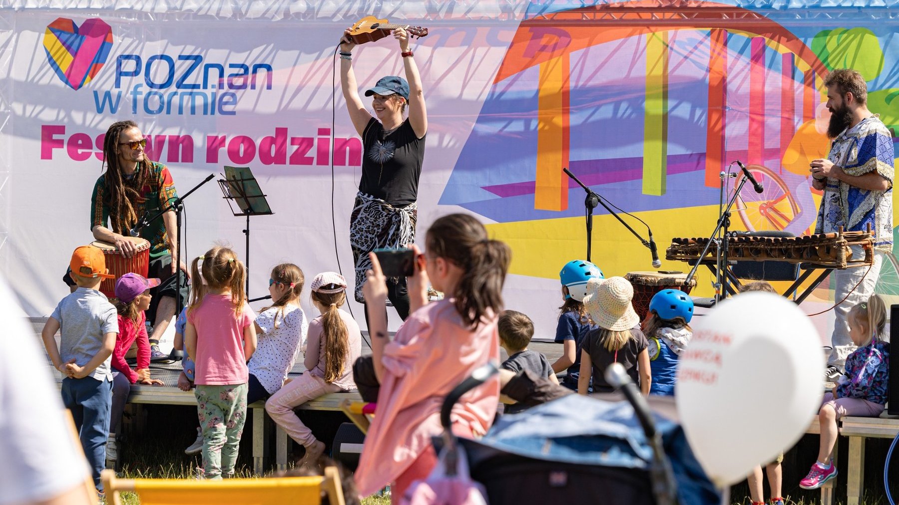 Zdjęcie z festynu - na scenie muzycy, przed sceną grupa dzieci