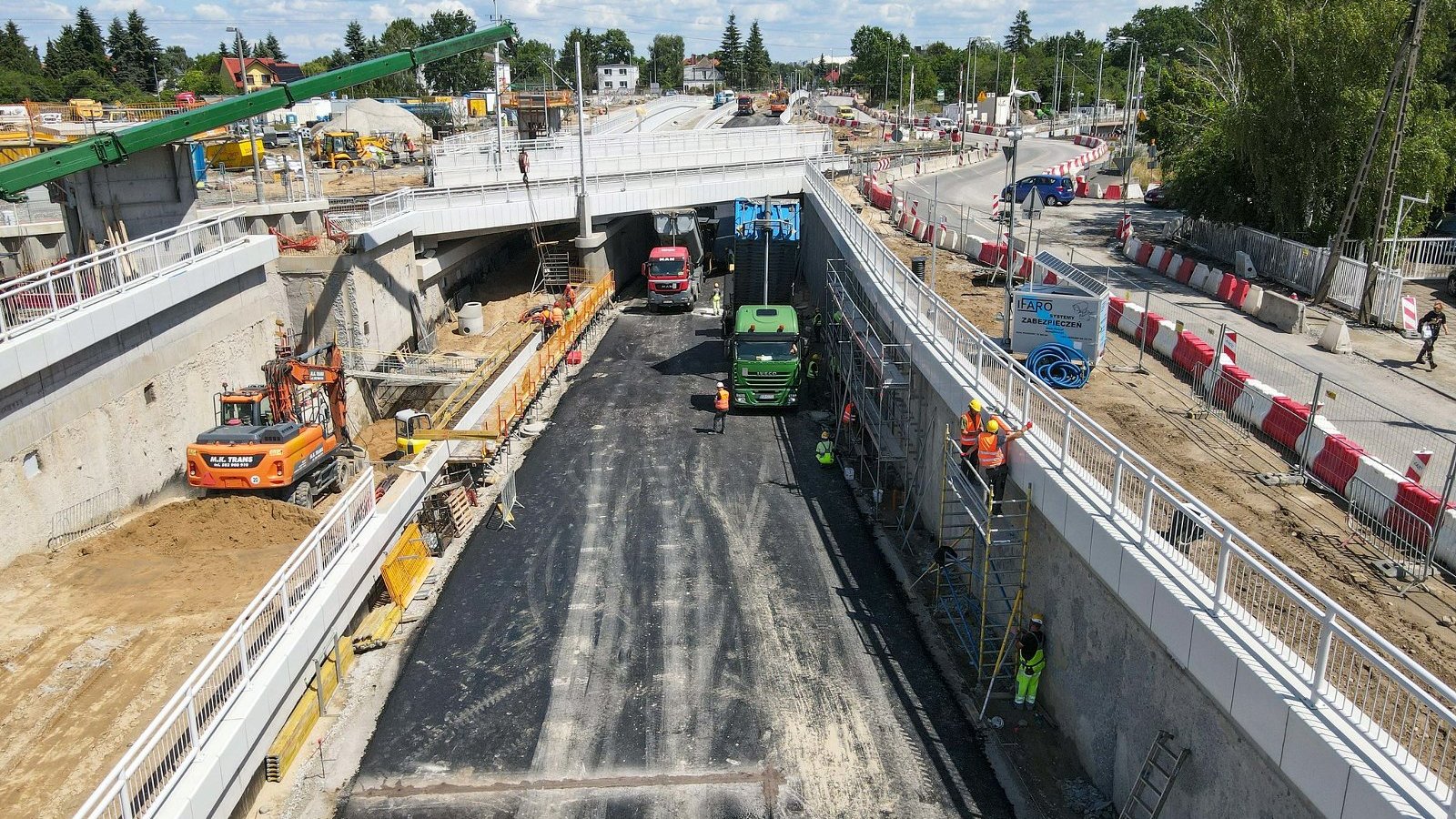 Galeria zdjęć - inwestycja widziana z lotu ptaka, w centrum zdjęć wiadukt, widać maszyny budowlane