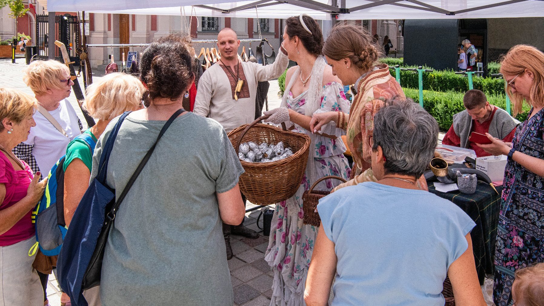 Na zdjęciu grupa osób na placu Kolegiackim, kobieta rozdaje ziemniaki