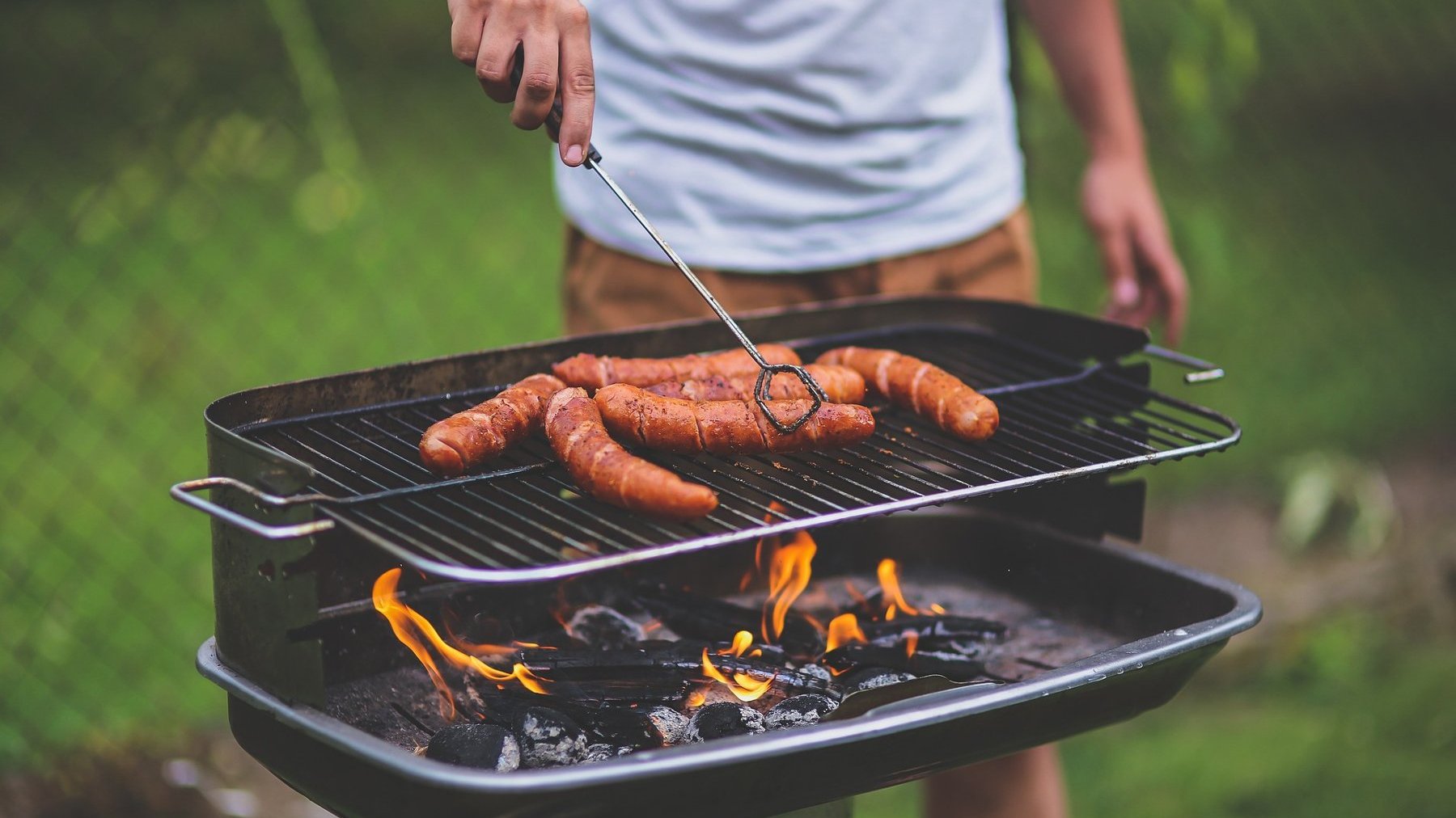 Zdjęcie przedstawia mężczyznę stojącego przy grillu.