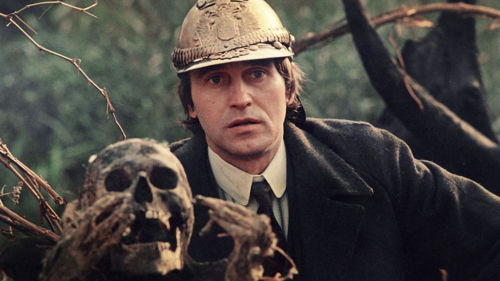 Na zdjęciu kadr z filmu, mężczyzna garniturze i w hełmie, obok czaszka