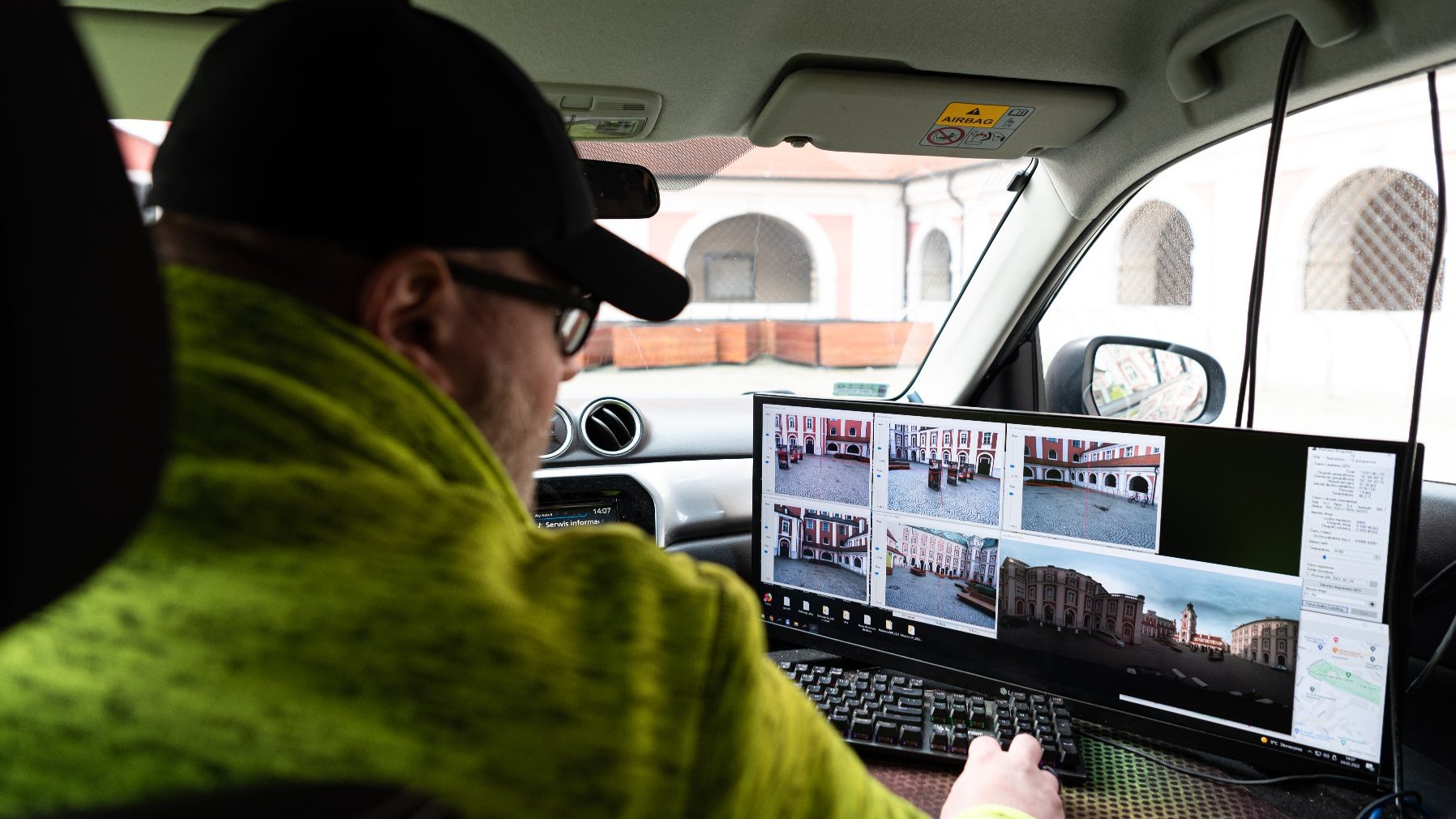 Zdjęcie przedstawia kierowce samochodu, który patrzy na moniitor, na którym widać obraz z kamer umieszczonych na dachu pojazdu.