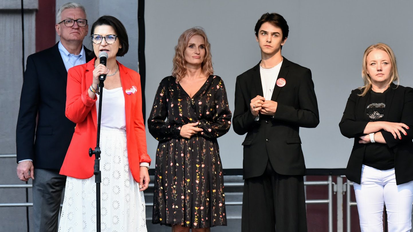 Na zdjęciu kilka osób na scenie, kobieta - Marta Mazurek - przy mikrofonie
