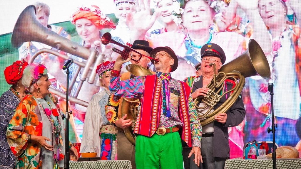 Na zdjęciu koncertujący seniorzy w kolorowych ubraniach
