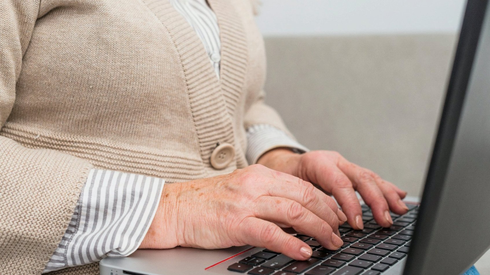 Na zdjęciu seniorka z laptopem, widać tylko jej dłonie