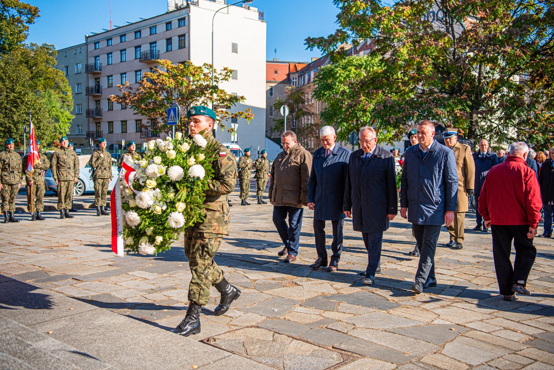 Na zdjęciu delegacja, przed nią żołnierz trzymający wiązankę - grafika artykułu