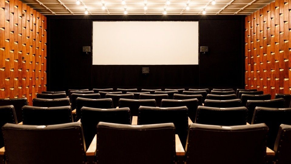 Na zdjęciu widać salę kinową - na pierwszym planie rzędy krzeseł, w tle ekran.