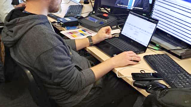 Na zdjęciu mężczyzna przy komputerze, przed nim dużo ekranów