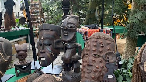 Galeria zdjęć przedsatwia afrykańskiej rzeźby i maski rozłożone na stole pokrytym zielonym suknem.