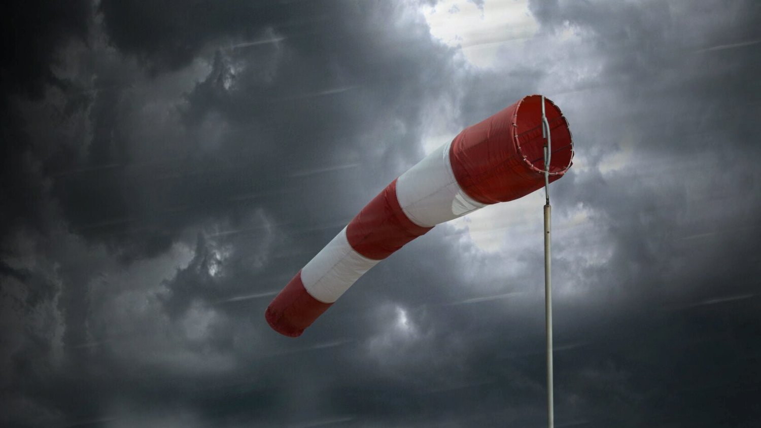 Zdjęcie przedstawia biało-czerowny wiatrowskaz na tle zachmurzonego nieba. - grafika artykułu