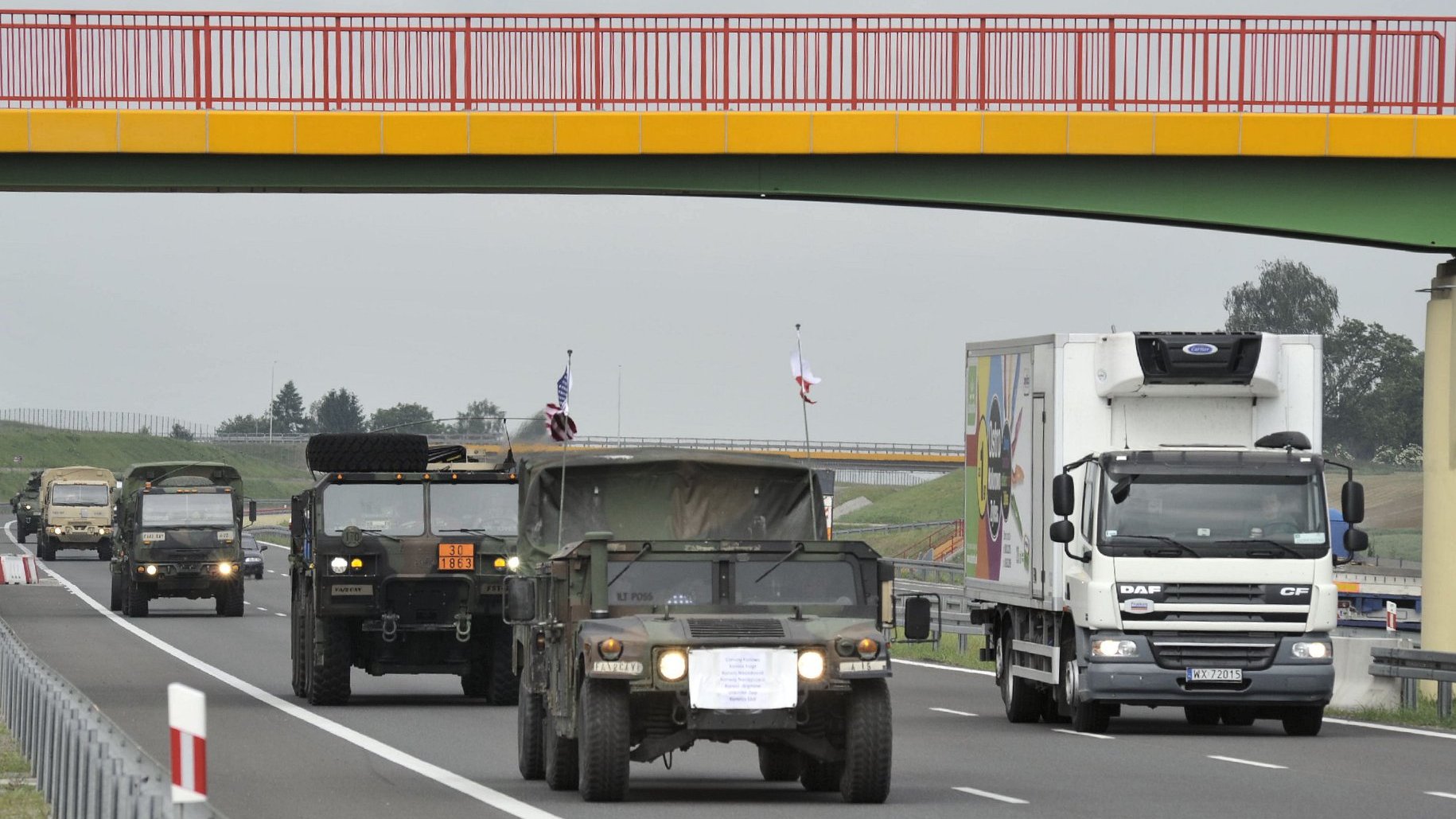 Na zdjęciu widać samochody wojskowe na drodze.
