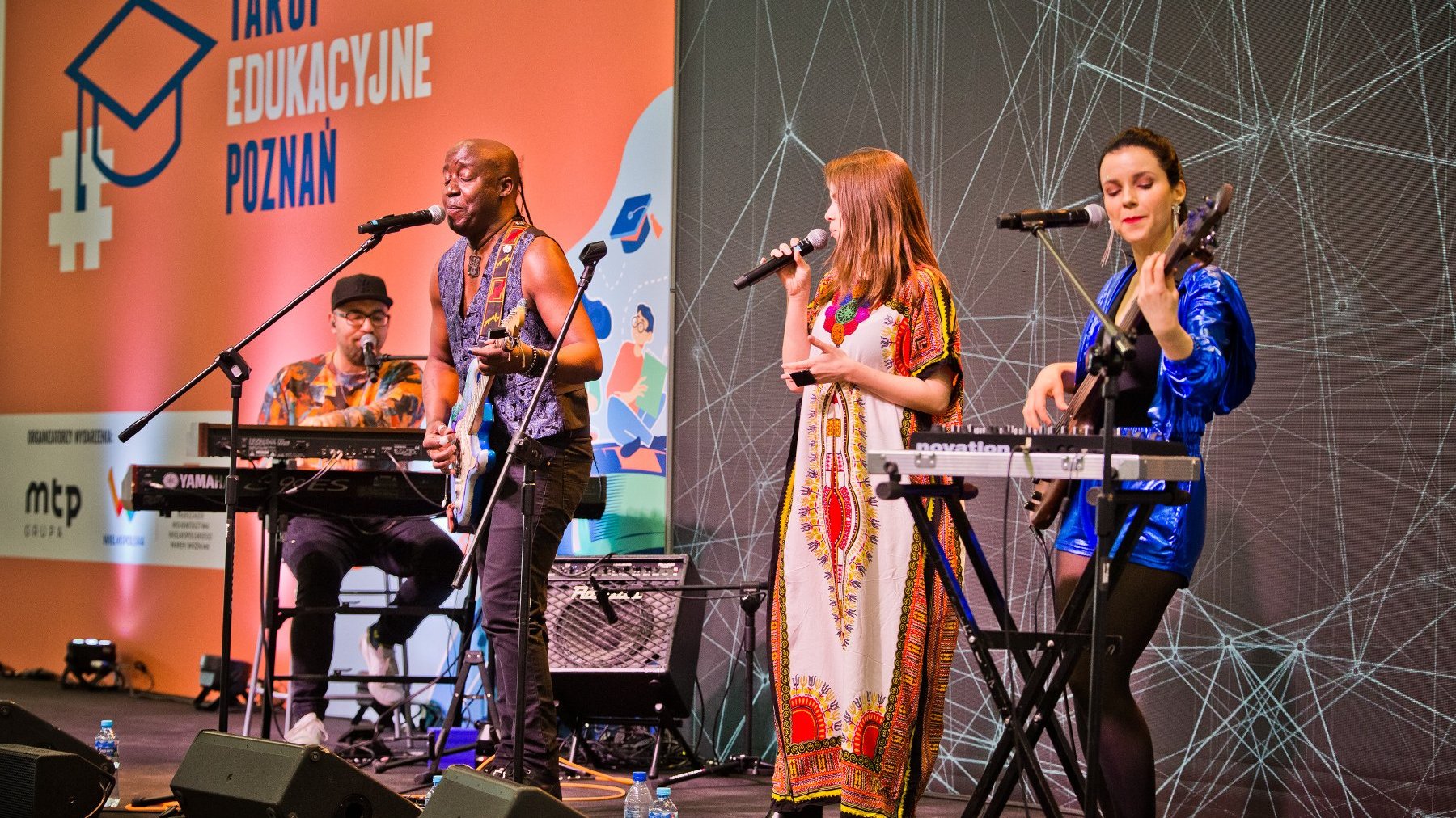 Zdjęcie przedstawia muzyków z instrumentami na scenie - dwie kobiety i dwóch mężczyzn.