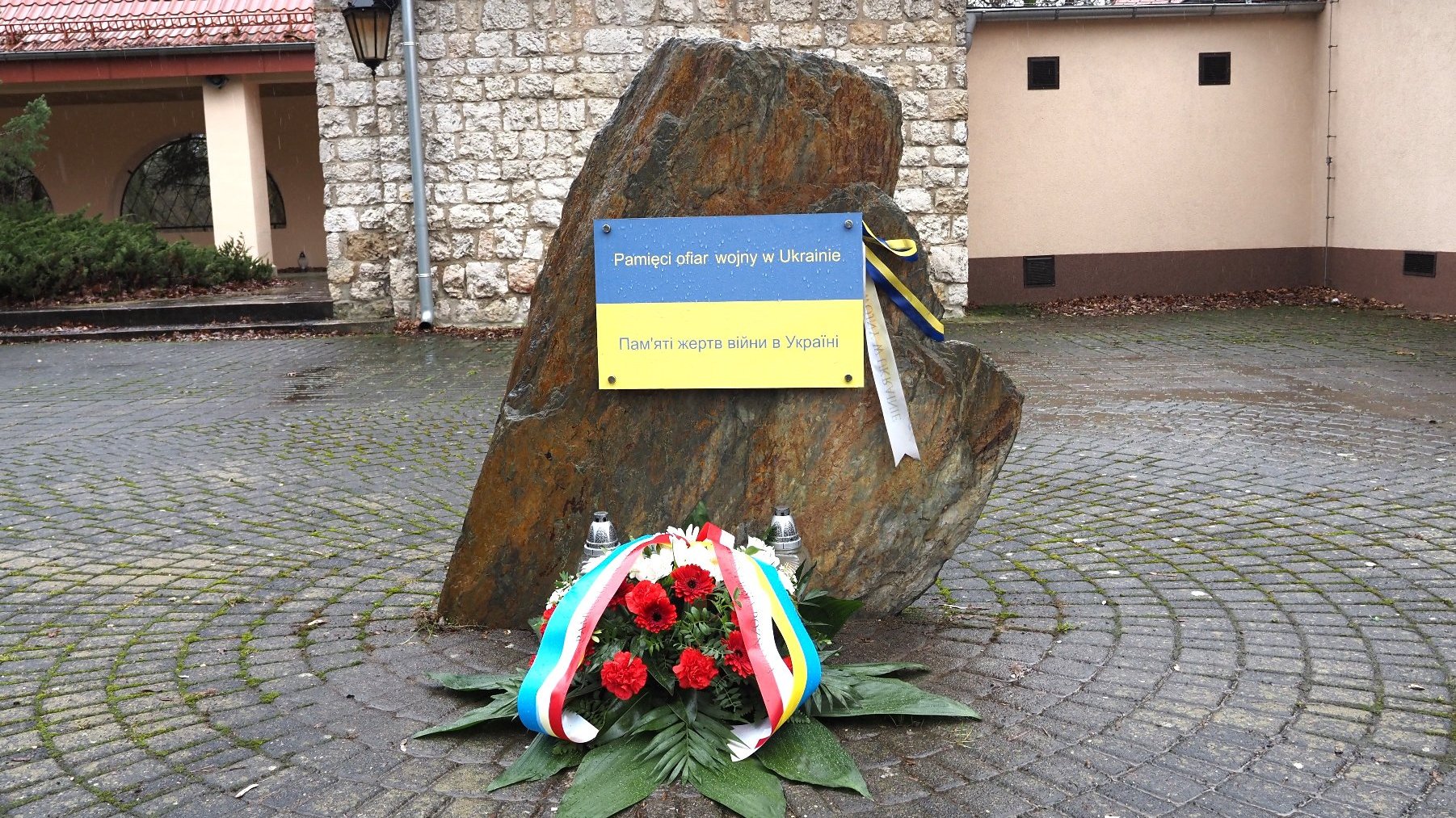 Zdjęcie przedstawia kwiaty pod pomnikiem.