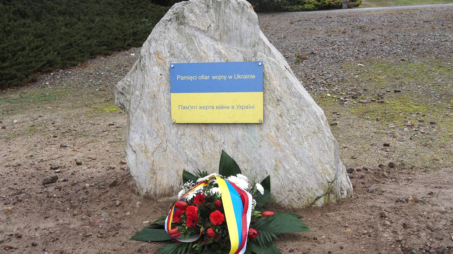 Zdjęcie przedstawia kwiaty pod pomnikiem.