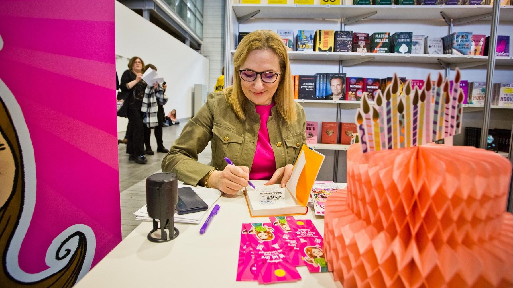 Na zdjęciu kobieta podpisująca książkę na stoisku