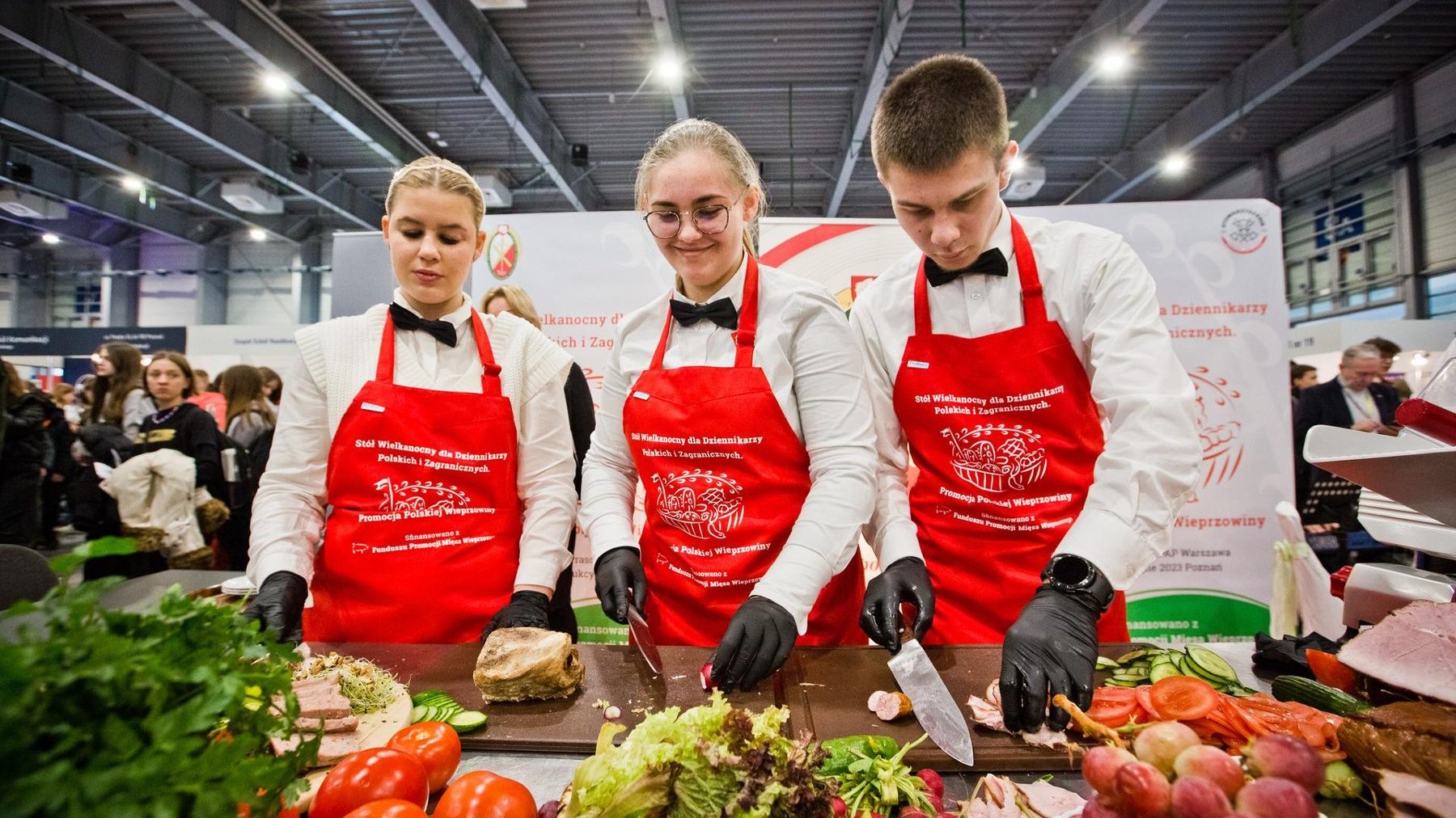 Na zdjęciu troje młodych ludzi w czerwonych fartuchach kucharskich
