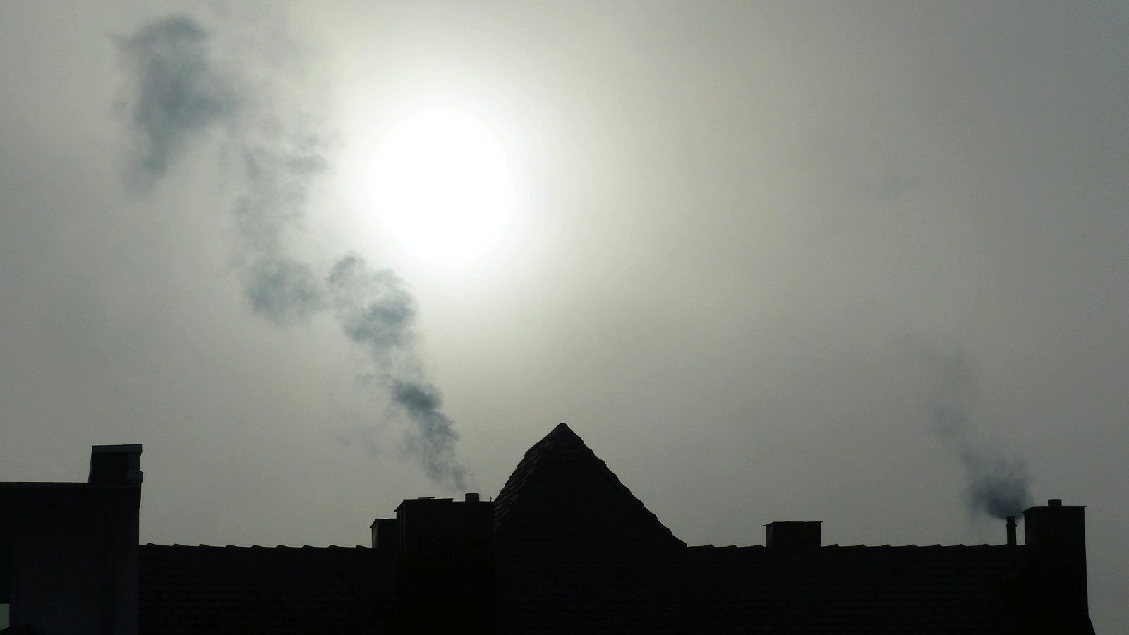 Zdjęcie przedstawia dymiący komin.