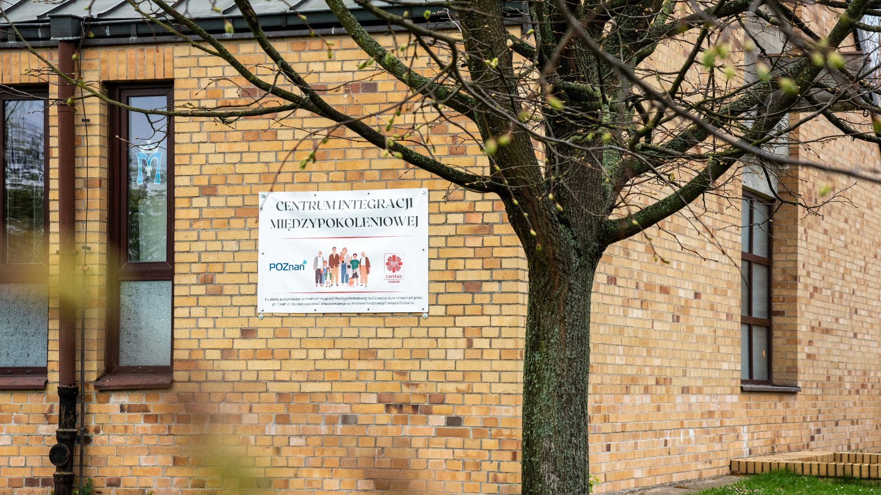 Na zdjęciu budynek, na nim baner z napisem centrum integracji międzypokoleniowej