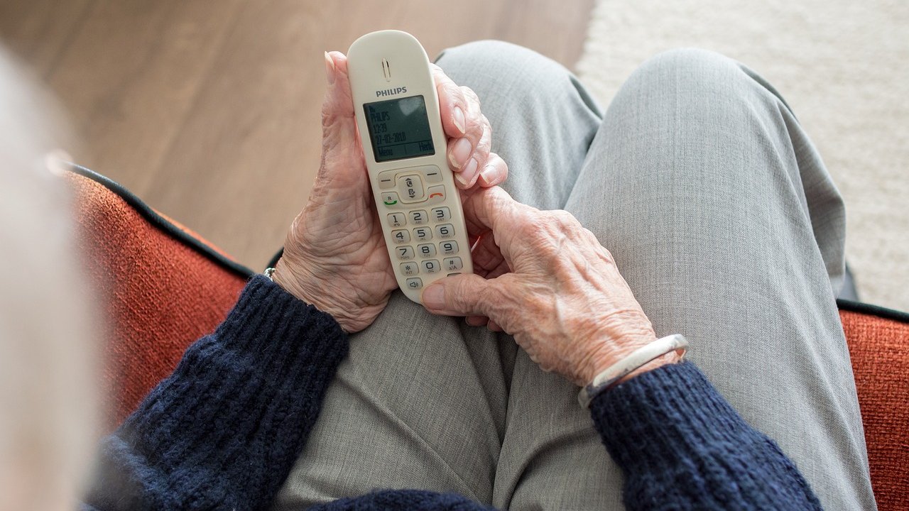 Na zdjęciu starsza kobieta trzymająca telefon, zdjęcie robione z góry