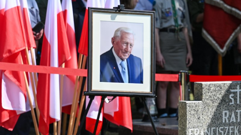 Na zdjęciu zdjęcie zmarłego, w tle flagi Polski