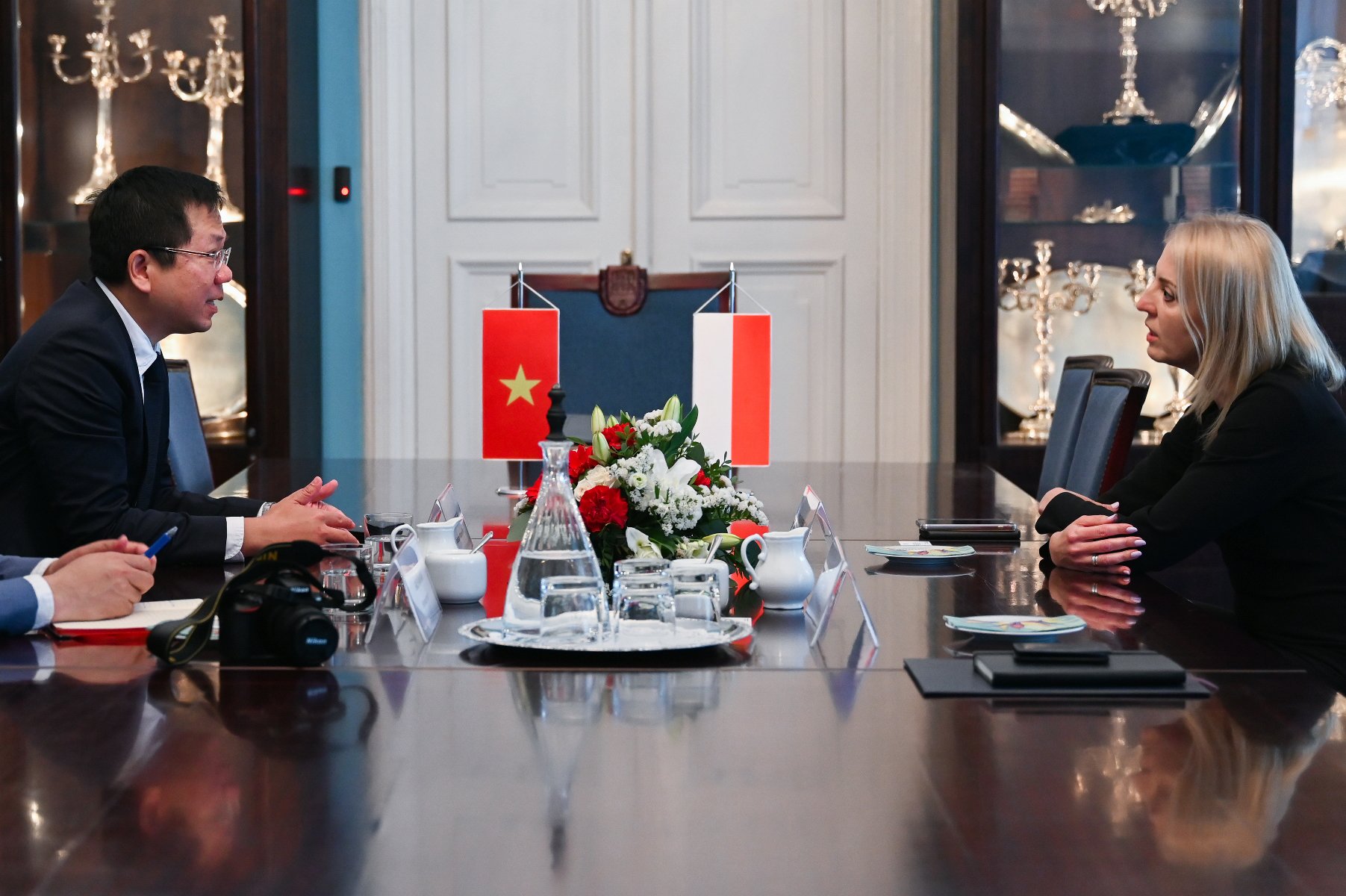 Na zdjęciu ambasador i zastępczyni prezydenta siedzący przy stole, rozmawiają - grafika artykułu