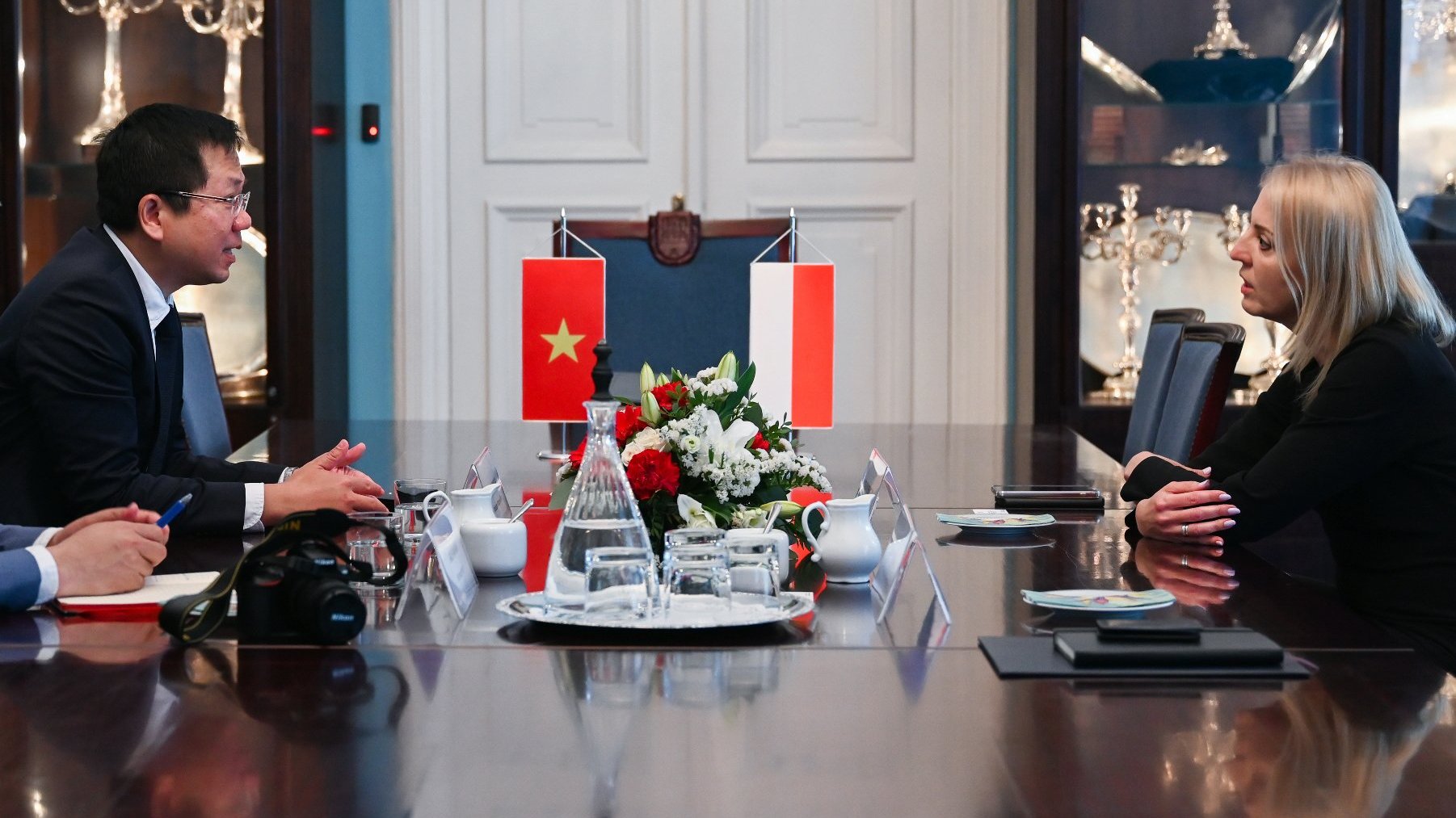 Na zdjęciu ambasador i zastępczyni prezydenta siedzący przy stole, rozmawiają