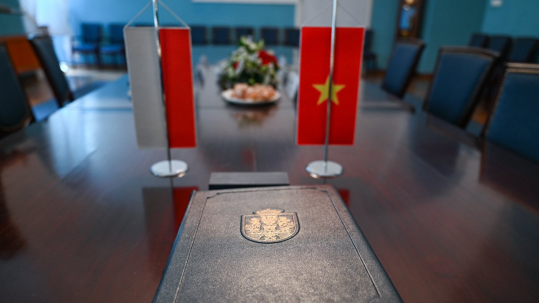 Na zdjęciu księga pamiątkowa na tle flag polskiej i wietnamskiej