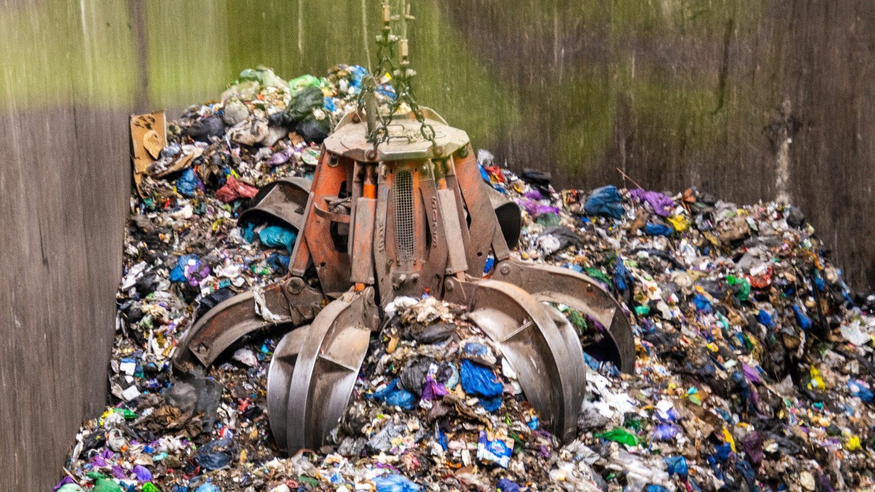 Zdjęcie przedstawia śmieci podnoszone specjalną maszyną.