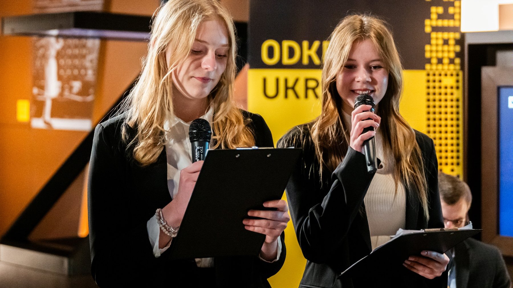 Zdjęcie przedstawia dwie młode dziewczyny trzymające mikrofony.