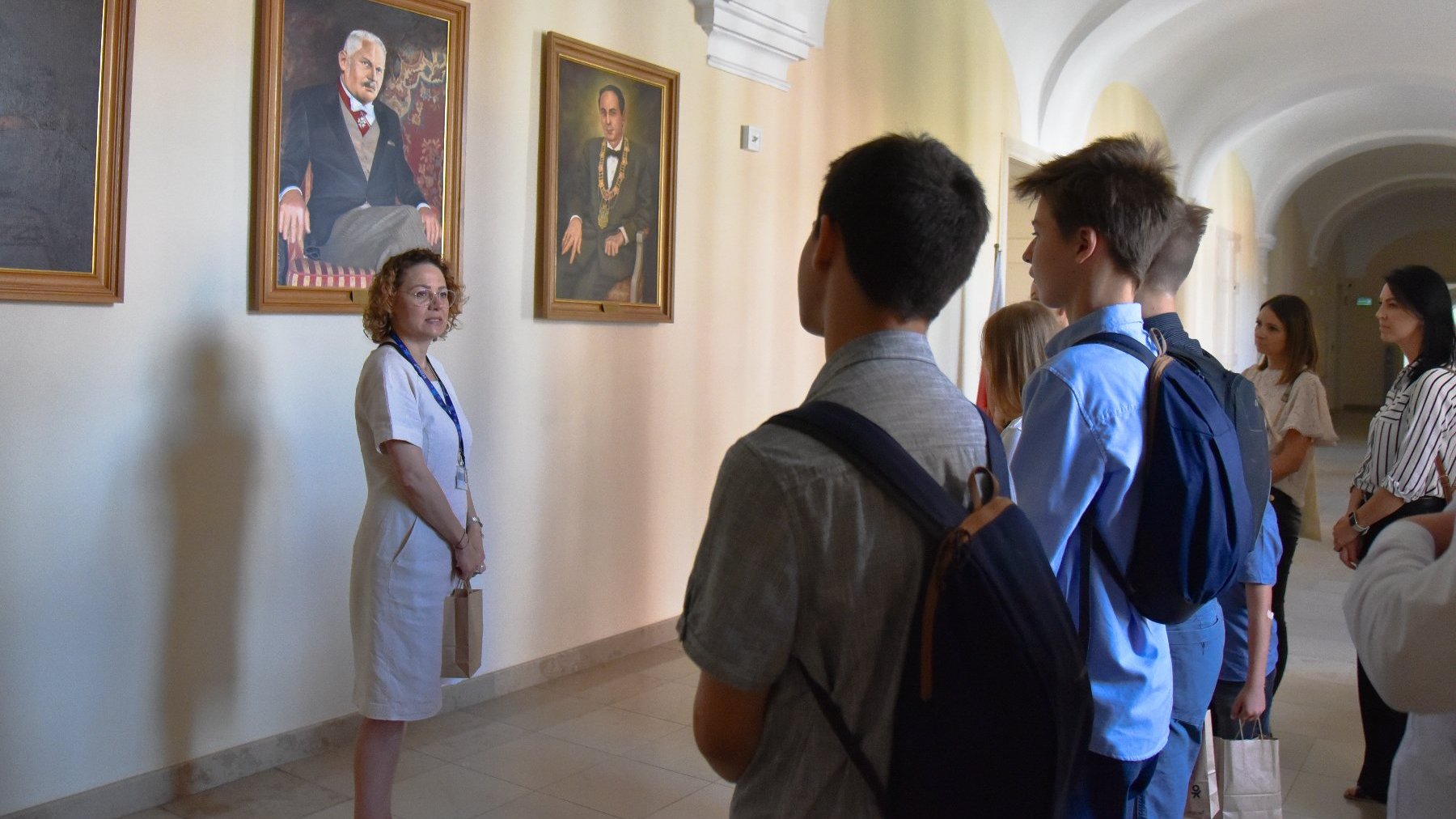 Na zdjęciu uczniowie patrzący na zawieszone w korytarzu portrety