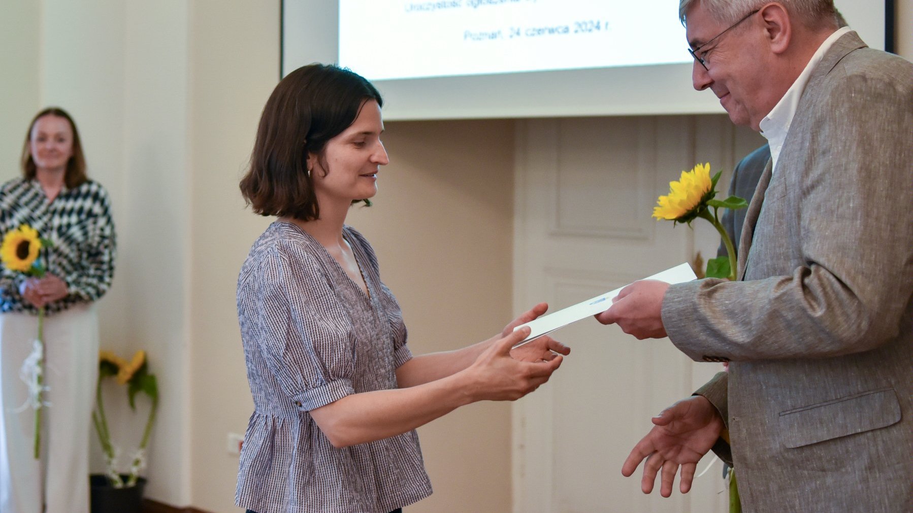 Na zdjęciu młoda kobieta odbierająca dyplom z rąk mężczyzny