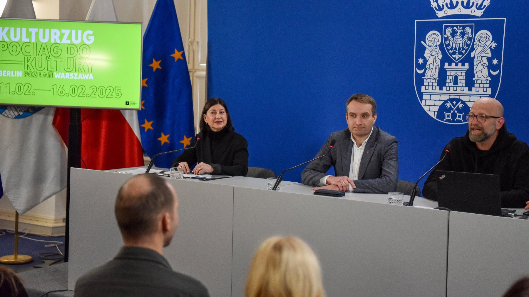 Na zdjęciu trzy osoby za stołem konferencyjnym, w tle ekran z napisem: pociąg do kultury