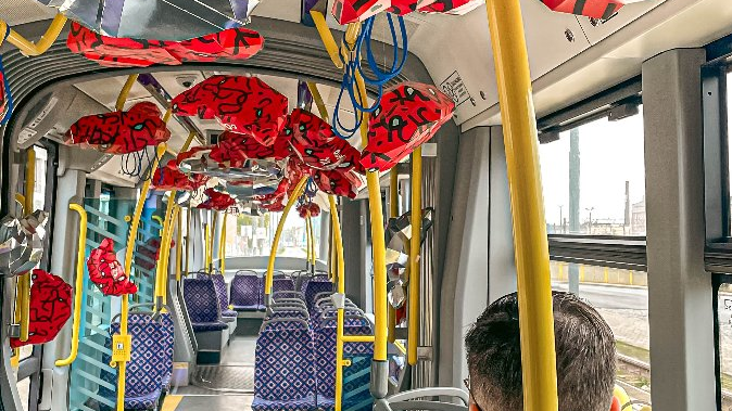 Zdjęcie przedstawia wnętrze tramwaju ozdobionego rogalami z kartonu oraz siedzącego mężczyznę.