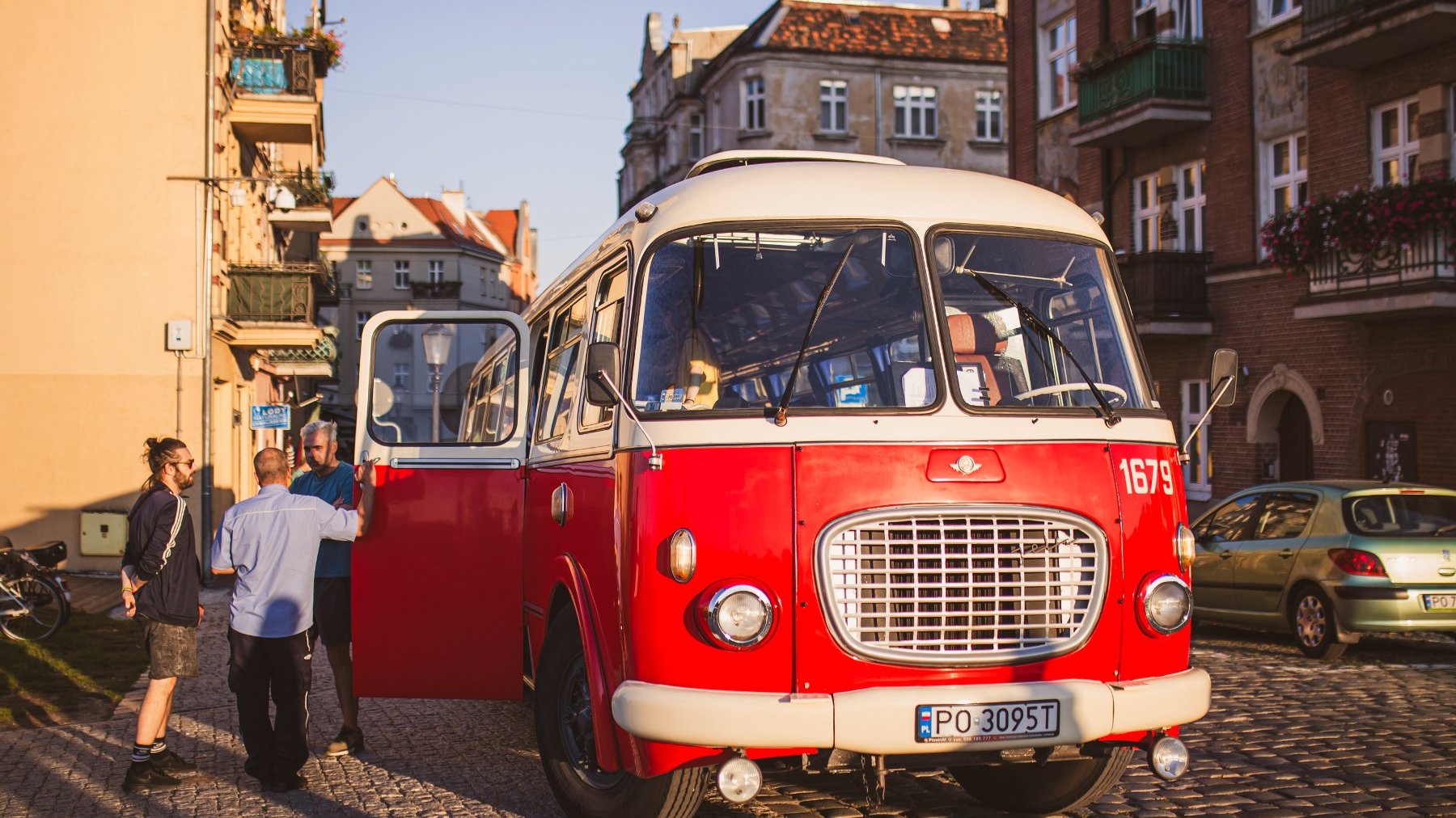 Zdjęcie przedstawia czerwony zabytkowy autobus.